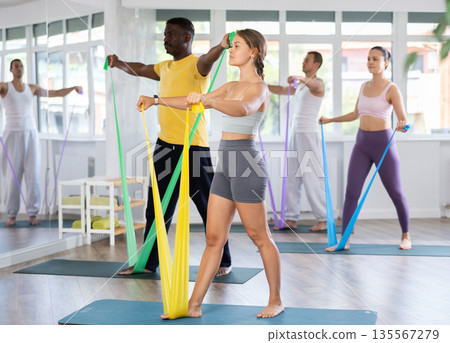 Fit girl exercising with resistance band in pilates class Fit girl exercising with resistance band in pilates class 135567279