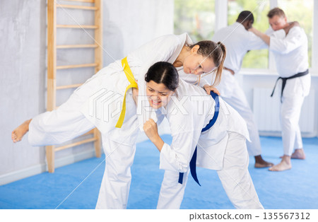 Female athletes playing Judo in sport hall Female athletes playing Judo in sport hall 135567312