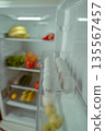 Open refrigerator filled with fresh fruits, vegetables, and eggs in a clear container, showcasing a healthy food selection and organized storage for meal preparation 135567457