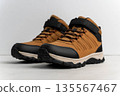 Brown hiking shoes with black accents and adjustable straps are positioned on a light background, showcasing their rugged design and outdoor suitability for trekking and adventure 135567467