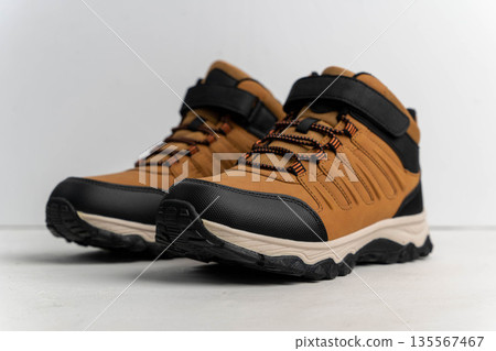 Brown hiking shoes with black accents and adjustable straps are positioned on a light background, showcasing their rugged design and outdoor suitability for trekking and adventure 135567467