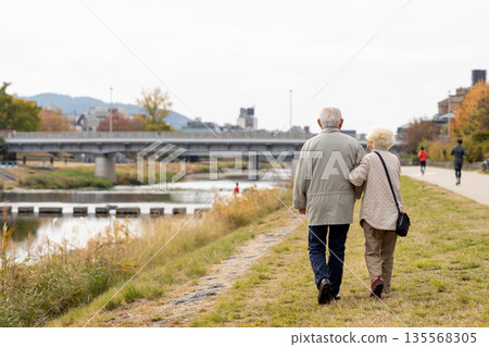 An elderly couple with gray hair walking along the Kamo River in Kyoto An elderly couple with gray hair walking along the Kamo River in Kyoto 135568305