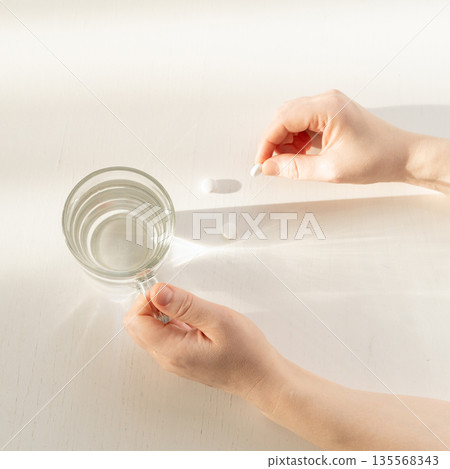 Person taking medication with glass of water Person taking medication with glass of water 135568343