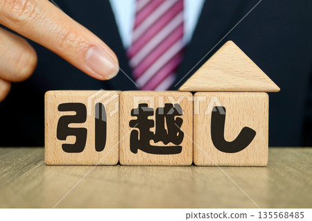 A man in a suit and wooden blocks indicating a move. A man in a suit and wooden blocks indicating a move. 135568485