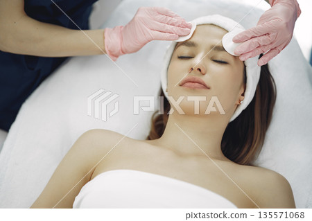 Cosmetologist treats client's skin. Woman with cosmetologist. Lady in a beauty studio. Cosmetologist treats client's skin. Woman with cosmetologist. Lady in a beauty studio. 135571068