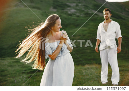 Man and woman in the mountains. Young couple in love at sunset. Woman in a blue dress. 135571097