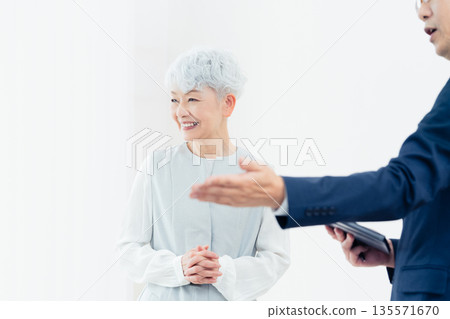 Senior woman listening to a salesperson's explanation Senior woman listening to a salesperson's explanation 135571670
