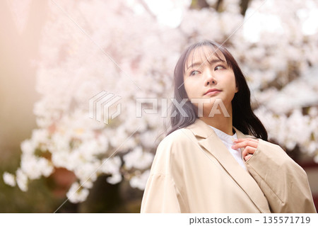 一位年輕的亞洲女性正在欣賞櫻花。 135571719