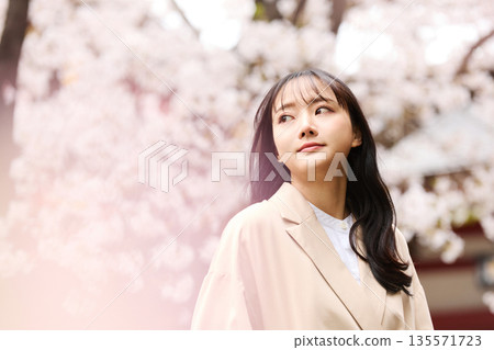 一位年輕的亞洲女性正在欣賞櫻花。 135571723