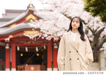 一位年輕的亞洲女性正在欣賞櫻花。 135571734