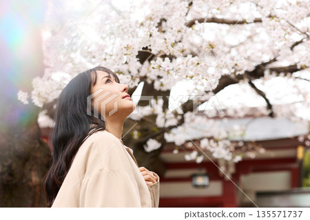 一位年輕的亞洲女性正在欣賞櫻花。 135571737