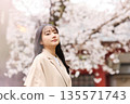 一位年輕的亞洲女性正在欣賞櫻花。 135571743