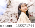 一位年輕的亞洲女性正在欣賞櫻花。 135571744