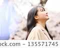 一位年輕的亞洲女性正在欣賞櫻花。 135571745