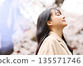 一位年輕的亞洲女性正在欣賞櫻花。 135571746
