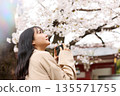 一位年輕的亞洲女性正在欣賞櫻花。 135571755