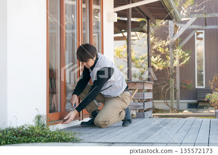 A man in work clothes repairing a window A man in work clothes repairing a window 135572173