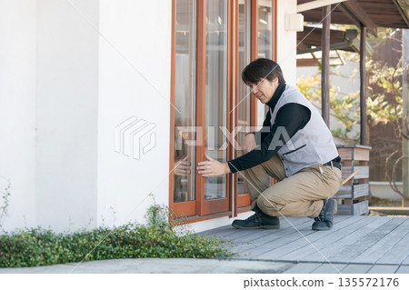 A man in work clothes repairing a window 135572176