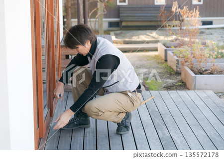 A man in work clothes repairing a window 135572178