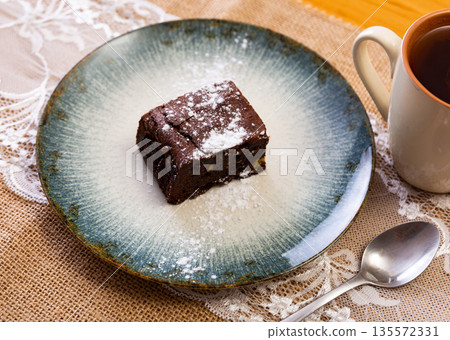 Restaurant serves dessert - ceramic plate accommodates small piece of brownie sponge cake 135572331