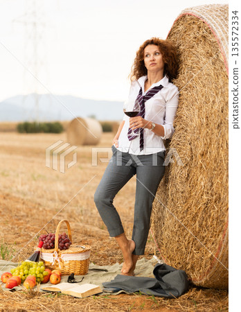 Relaxed woman in business attire enjoying wine during country retreat 135572334