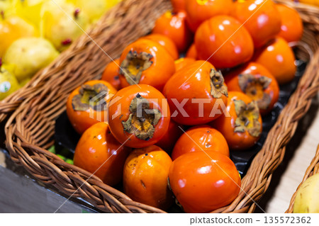 High quality imported eco persimmon grouped stored in window in wicker basket. High quality imported eco persimmon grouped stored in window in wicker basket. 135572362