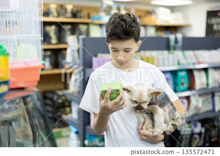 Teenager with Yorkshire terrier choosing dry dog food in pet store Teenager with Yorkshire terrier choosing dry dog food in pet store 135572471
