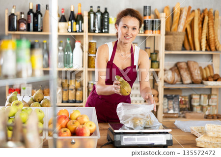 Supermarket produce department worker weighs pears on scales for sale Supermarket produce department worker weighs pears on scales for sale 135572472