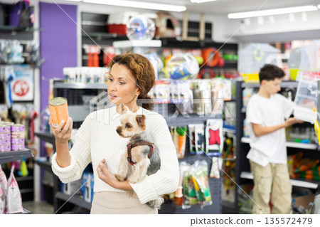 Female shopper selecting canned dog food for Yorkie in pet store Female shopper selecting canned dog food for Yorkie in pet store 135572479