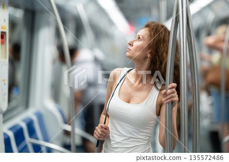 Adult woman stands in subway car 135572486