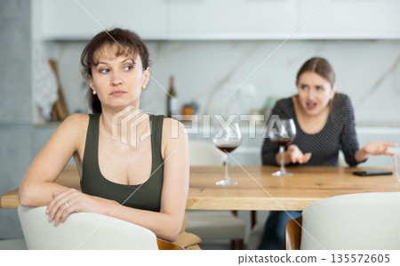 Two women have unpleasant conversation in dining room 135572605