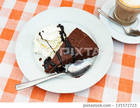 Restaurant serves dessert - ceramic plate accommodates small piece of brownie sponge cake Restaurant serves dessert - ceramic plate accommodates small piece of brownie sponge cake 135572723