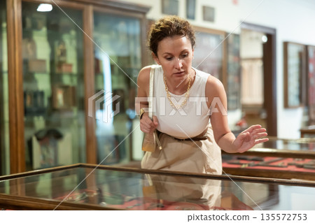 Woman visit museum, examines masterpiece at exhibition 135572753