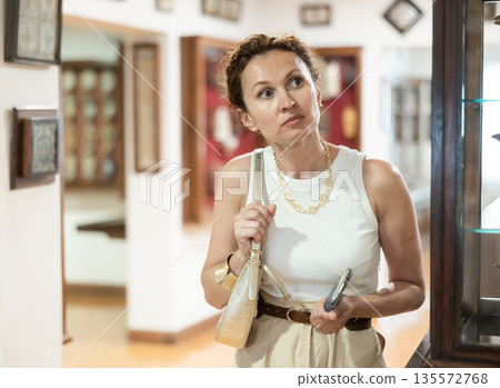 Thoughtful woman examining historacal exhibits in museum 135572768