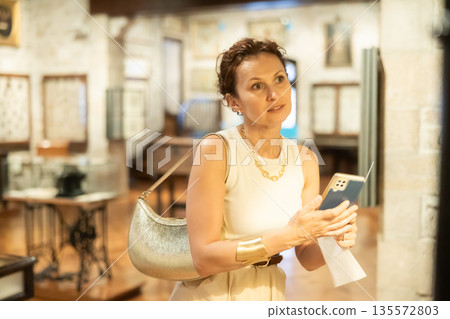 Female museum visitor taking photo of artifacts on smartphone 135572803