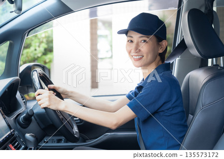 Middle-aged female delivery person delivering packages by car 135573172