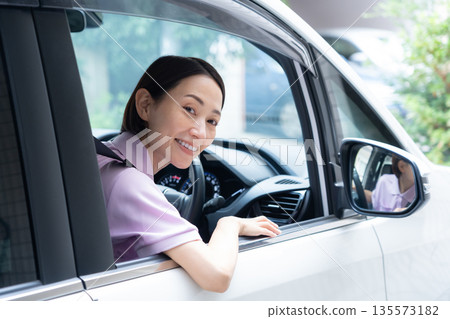 一位中年女性護理員駕車提供居家護理服務。 135573182