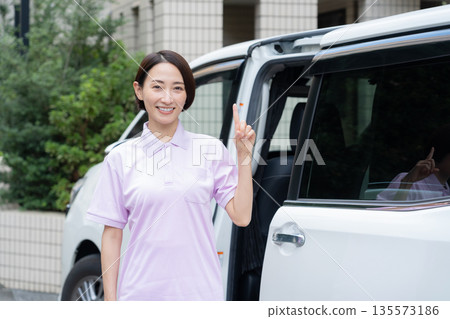 一位中年女性護理員駕車提供居家護理服務。 135573186