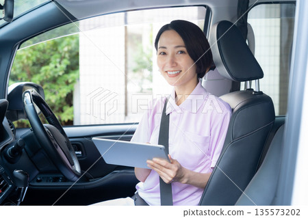 A middle-aged female caregiver providing home care by car A middle-aged female caregiver providing home care by car 135573202