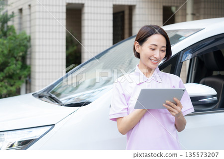 A middle-aged female caregiver providing home care by car 135573207
