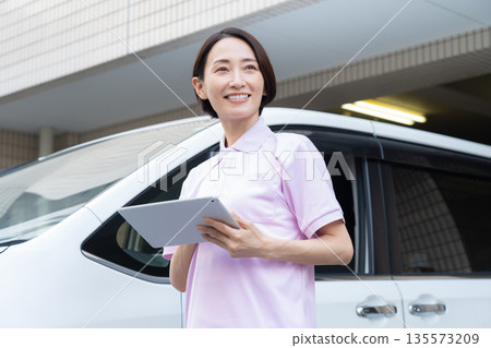 A middle-aged female caregiver providing home care by car 135573209