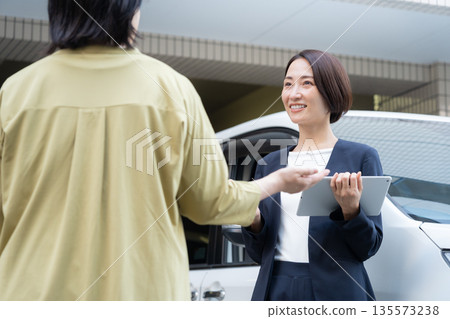 A middle-aged businesswoman assessing a car 135573238