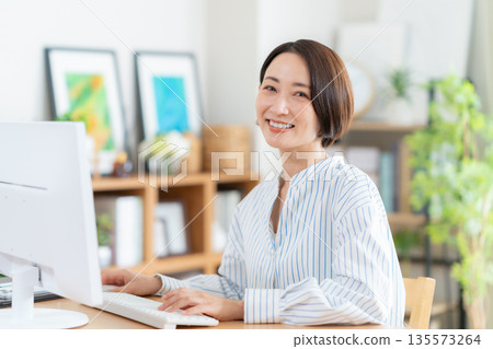 Middle-aged woman teleworking in the living room Middle-aged woman teleworking in the living room 135573264