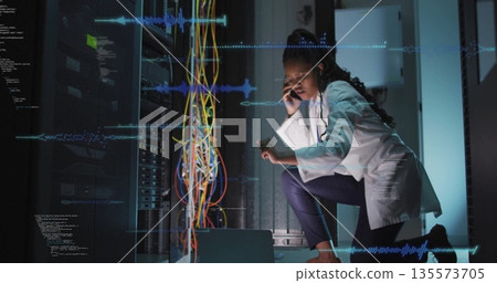 Engineer wearing lab coat inspecting multicolored cables in data center with smartphone, copy space Engineer wearing lab coat inspecting multicolored cables in data center with smartphone, copy space 135573705