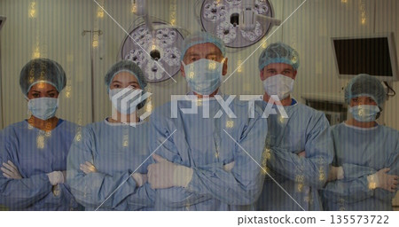 Standing medical team wearing blue gowns and masks in operating room with digital currency overlay 135573722