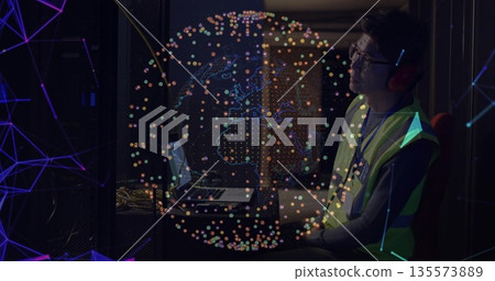 Tech wearing safety vest and headphones monitoring servers in server room, with globe, copy space 135573889