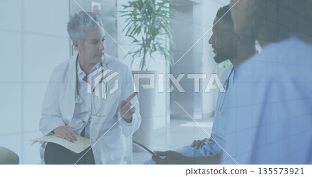 Pointing doctor wearing white coat holding file discussing care in hospital hallway, copy space Pointing doctor wearing white coat holding file discussing care in hospital hallway, copy space 135573921