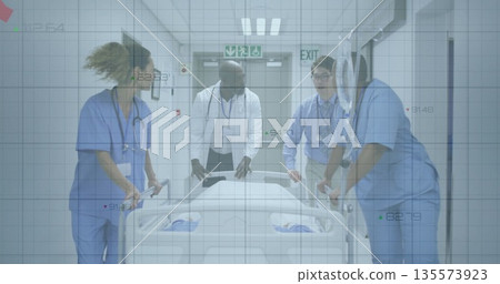 Walking medical team wearing scrubs and lab coat pushing gurney in hospital corridor with exit sign Walking medical team wearing scrubs and lab coat pushing gurney in hospital corridor with exit sign 135573923