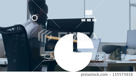 Working man typing code at office desk, with dual screens and patterned mug, copy space 135573938