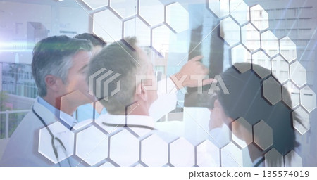 Four doctors in lab coats reviewing X-ray film on lightbox in clinic with stethoscopes Four doctors in lab coats reviewing X-ray film on lightbox in clinic with stethoscopes 135574019